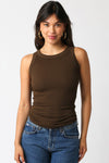 Woman wearing a brown tank top and blue jeans against a white background