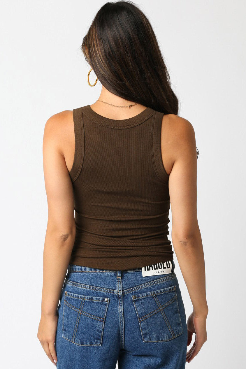 Person wearing a brown tank top and blue jeans on a white background