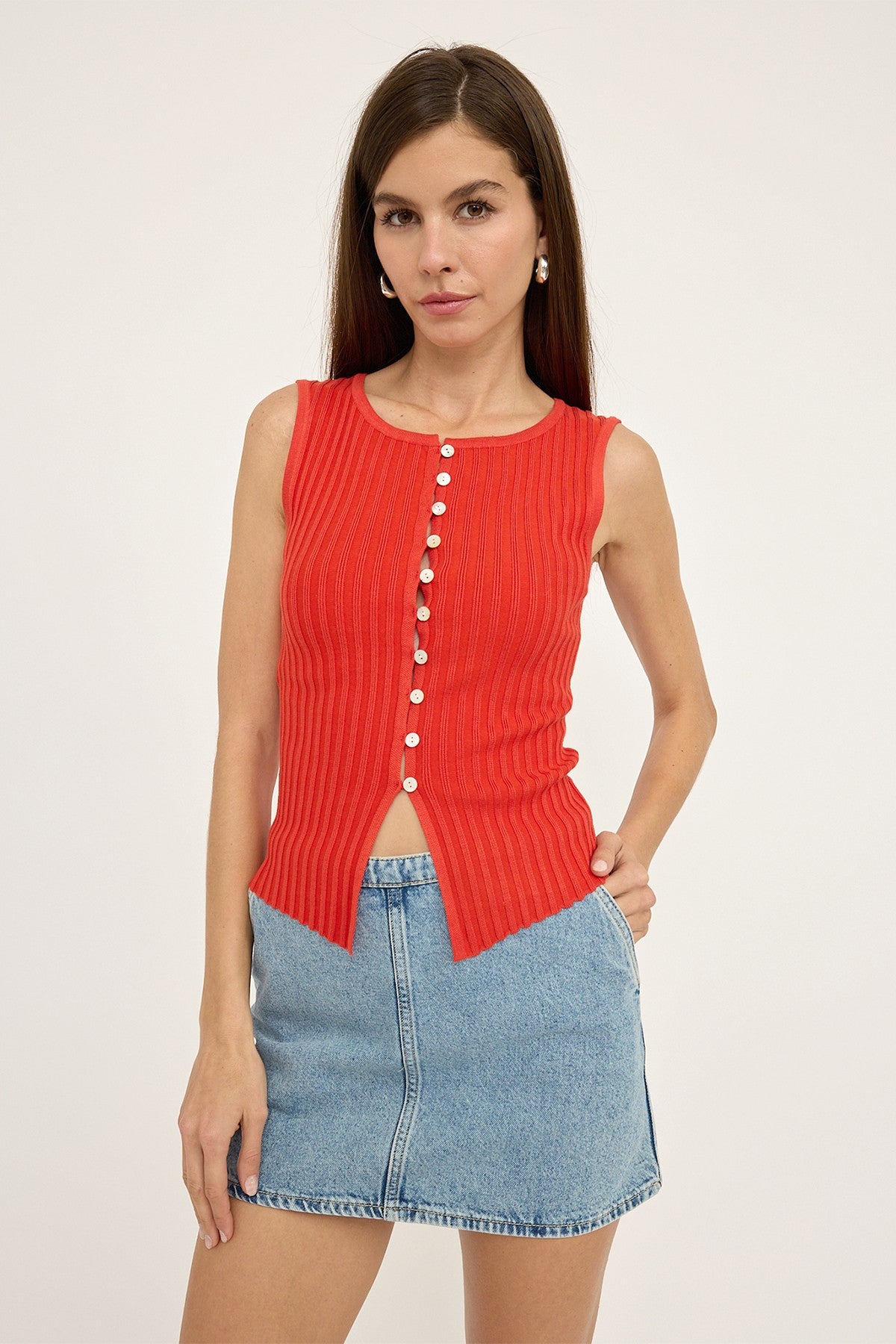 Woman wearing a red ribbed top with buttons and a denim skirt on a white background