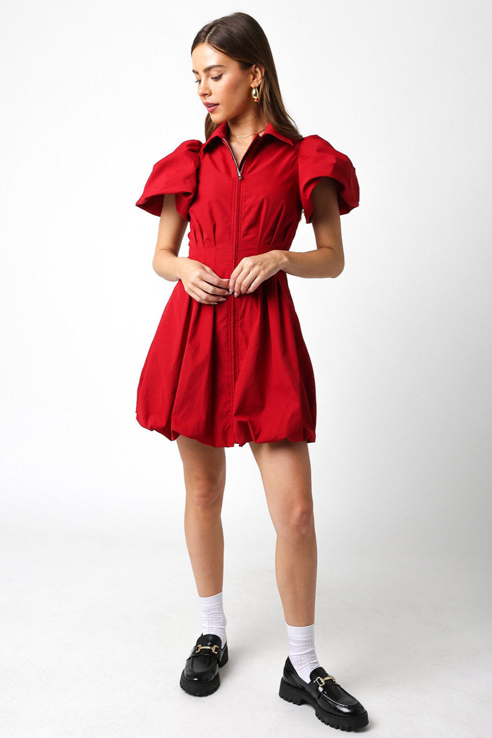 Woman wearing a red dress with puffed sleeves on a white background
