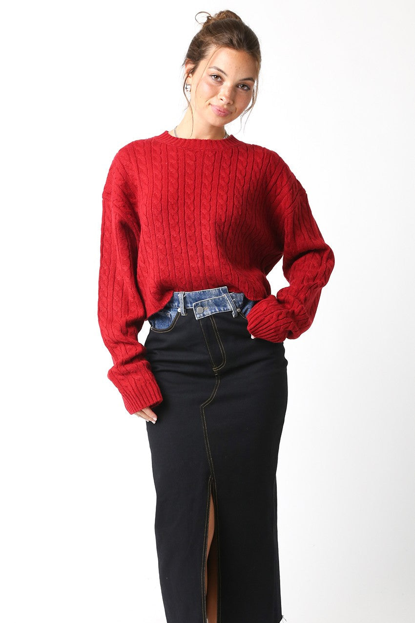 Woman wearing a red sweater and black skirt on a white background