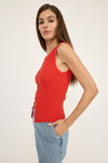 Woman wearing a red ribbed tank top and blue jeans on a white background