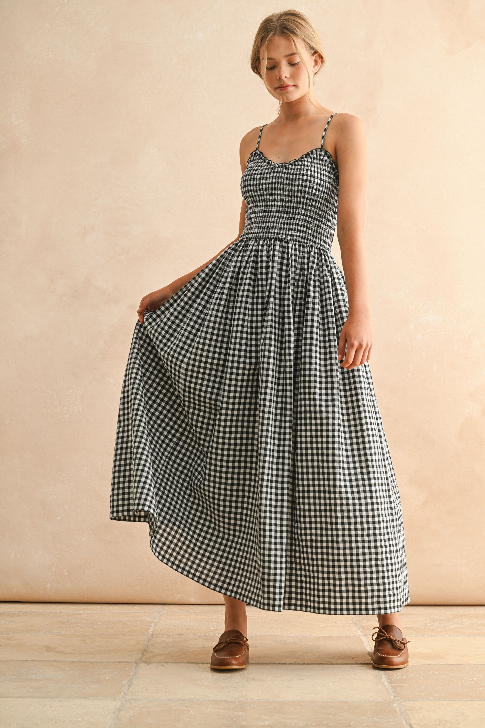 Woman wearing a black and white checkered dress against a beige background