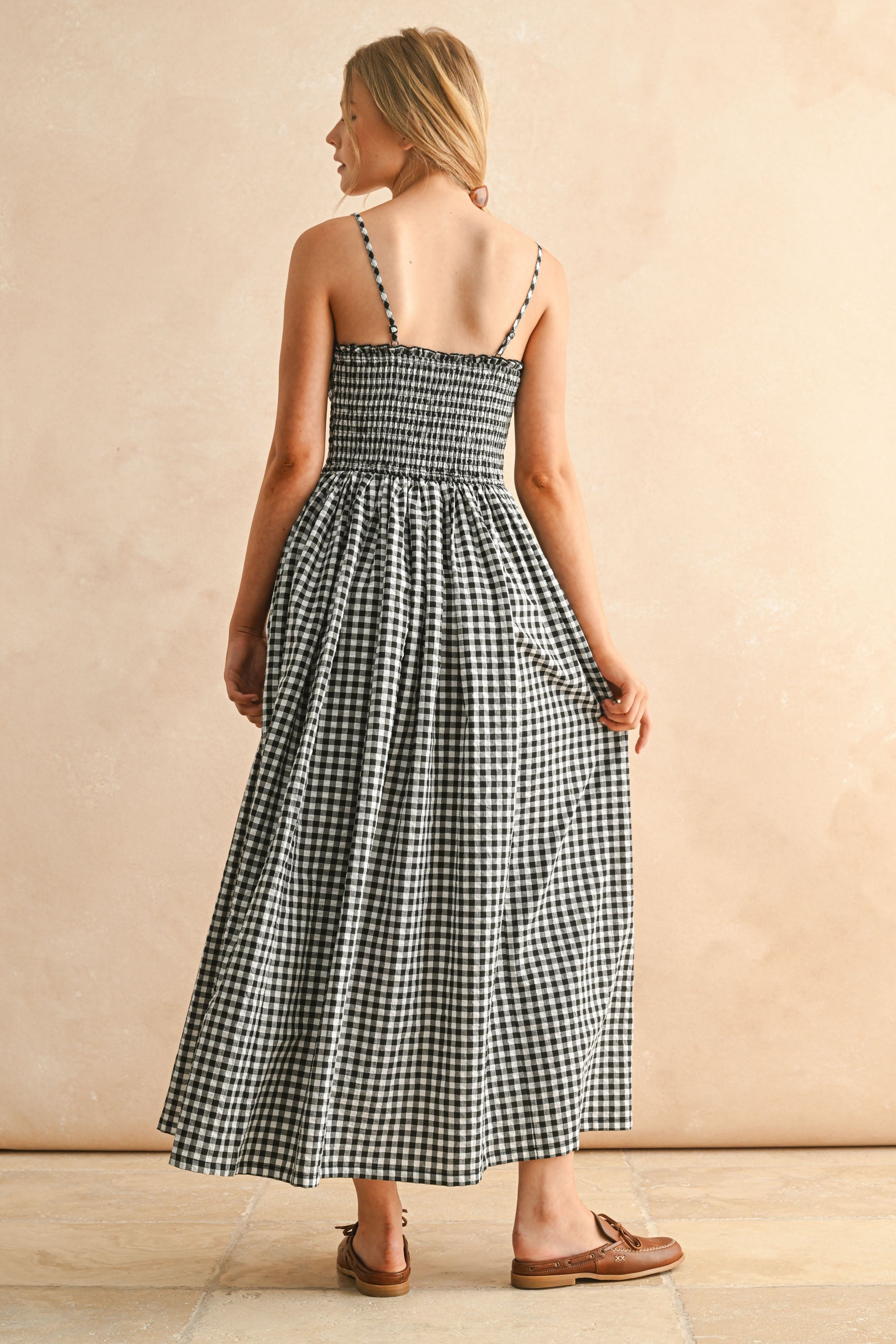 Woman wearing a black and white checkered dress against a beige background