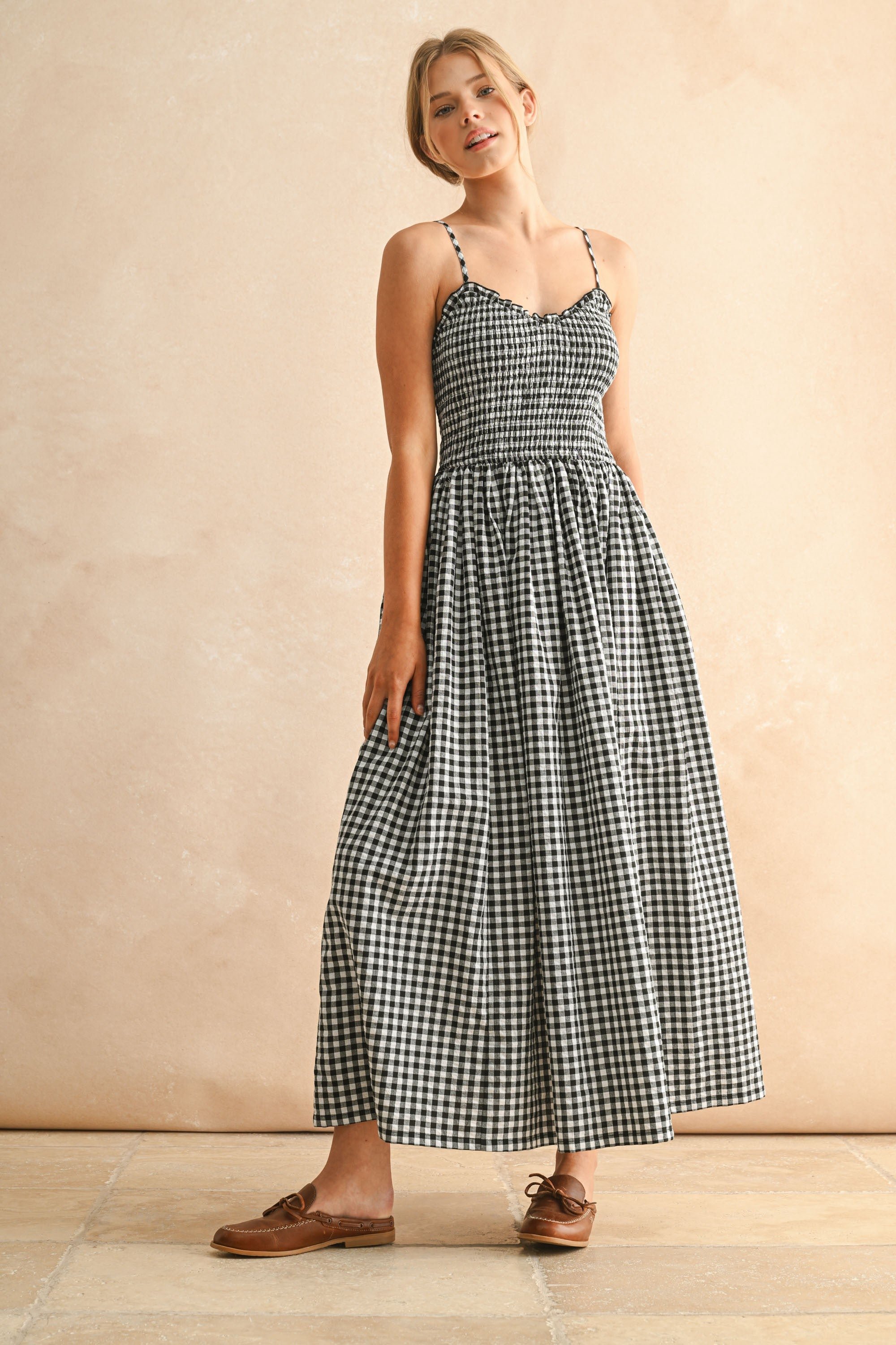 Woman wearing a black and white checkered dress against a beige background