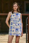 Woman wearing a sleeveless dress with blue and white pattern on a wooden deck.