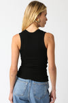Person wearing a black sleeveless top and blue jeans on a white background