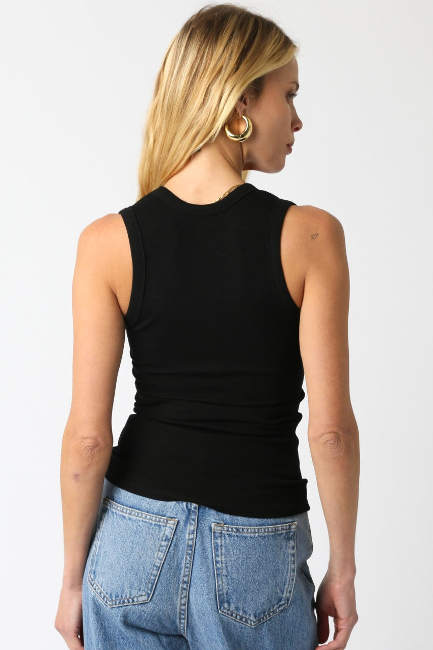 Person wearing a black sleeveless top and blue jeans on a white background