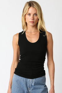 Woman wearing a black tank top and blue jeans on a white background