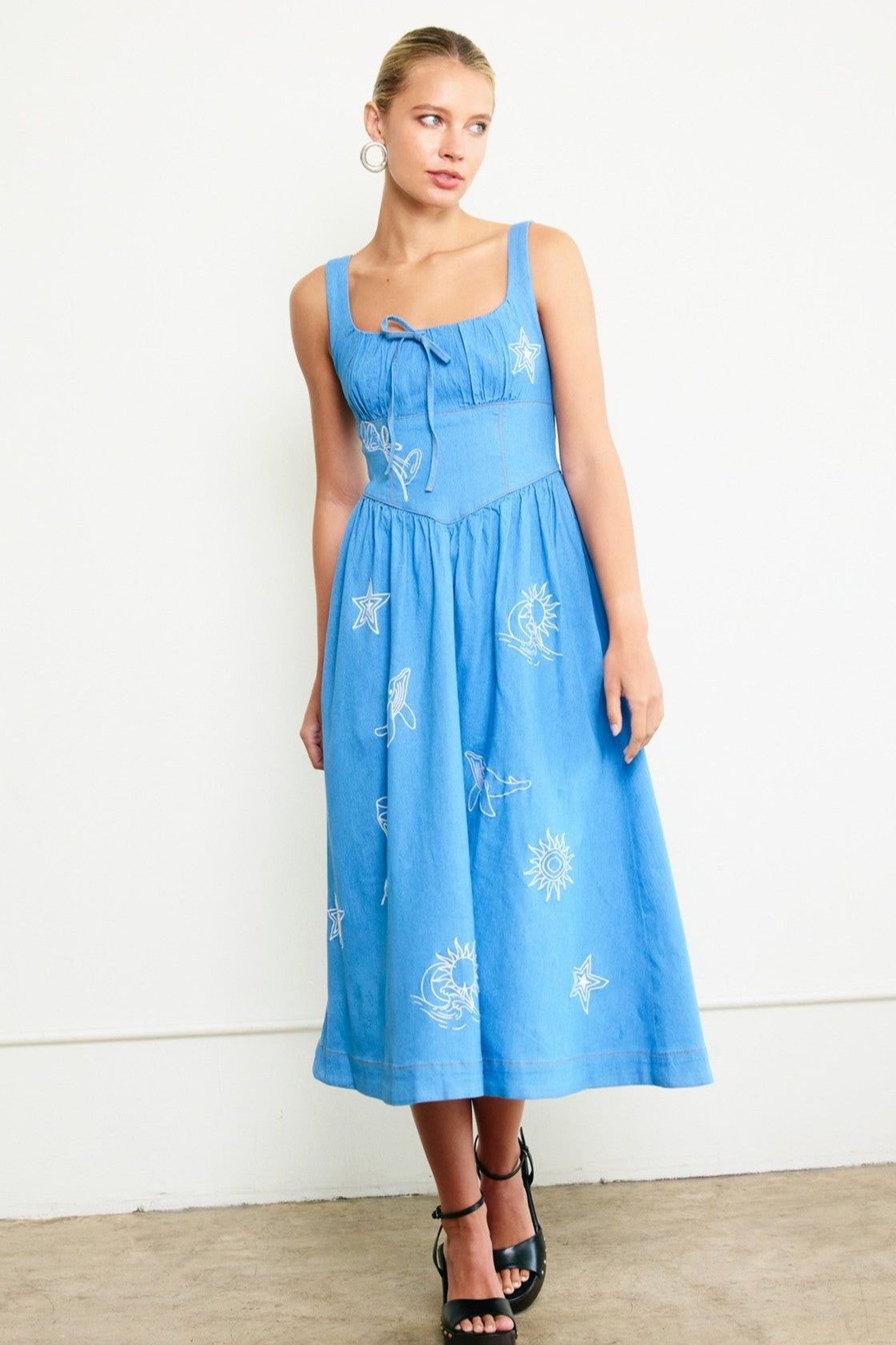 Woman wearing a blue dress with white floral patterns against a white background