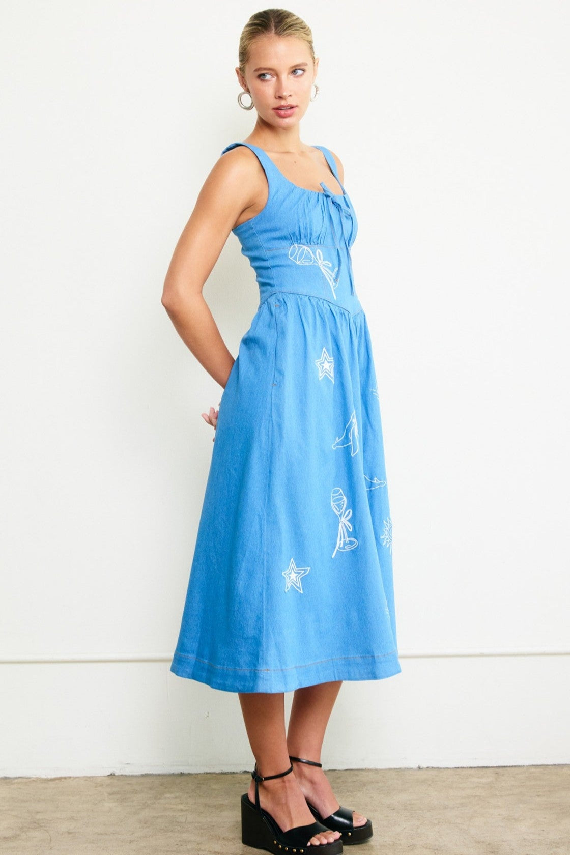 Woman wearing a blue dress with white patterns against a white background