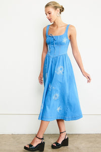 Woman wearing a blue dress with floral patterns against a white background