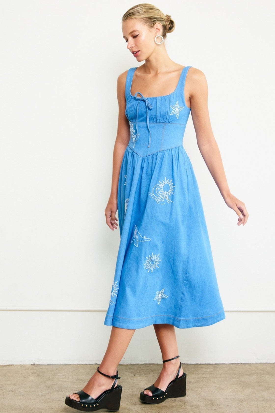 Woman wearing a blue dress with floral patterns against a white background