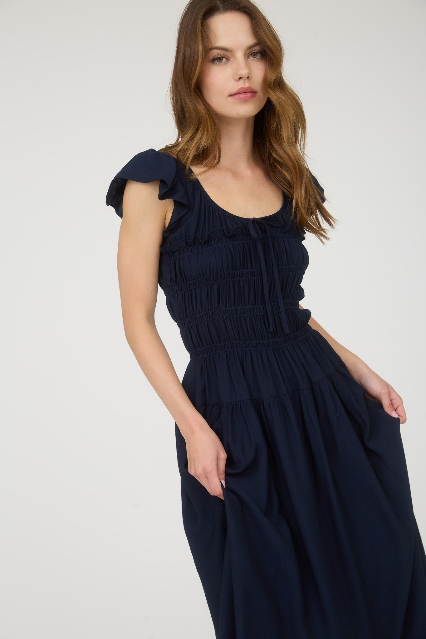 Woman wearing a navy blue dress with ruffled sleeves on a white background
