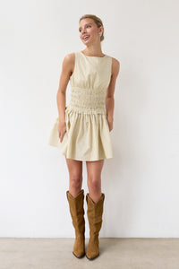 Woman wearing a light-colored dress and brown knee-high boots against a white background