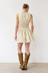 Woman wearing a beige dress and brown boots against a white background