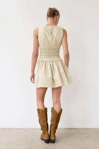 Woman wearing a beige dress and brown boots against a white background