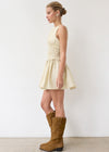 Woman wearing a light-colored dress and brown knee-high boots against a white background
