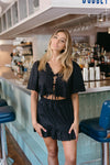 Woman in a black outfit standing in a bar setting