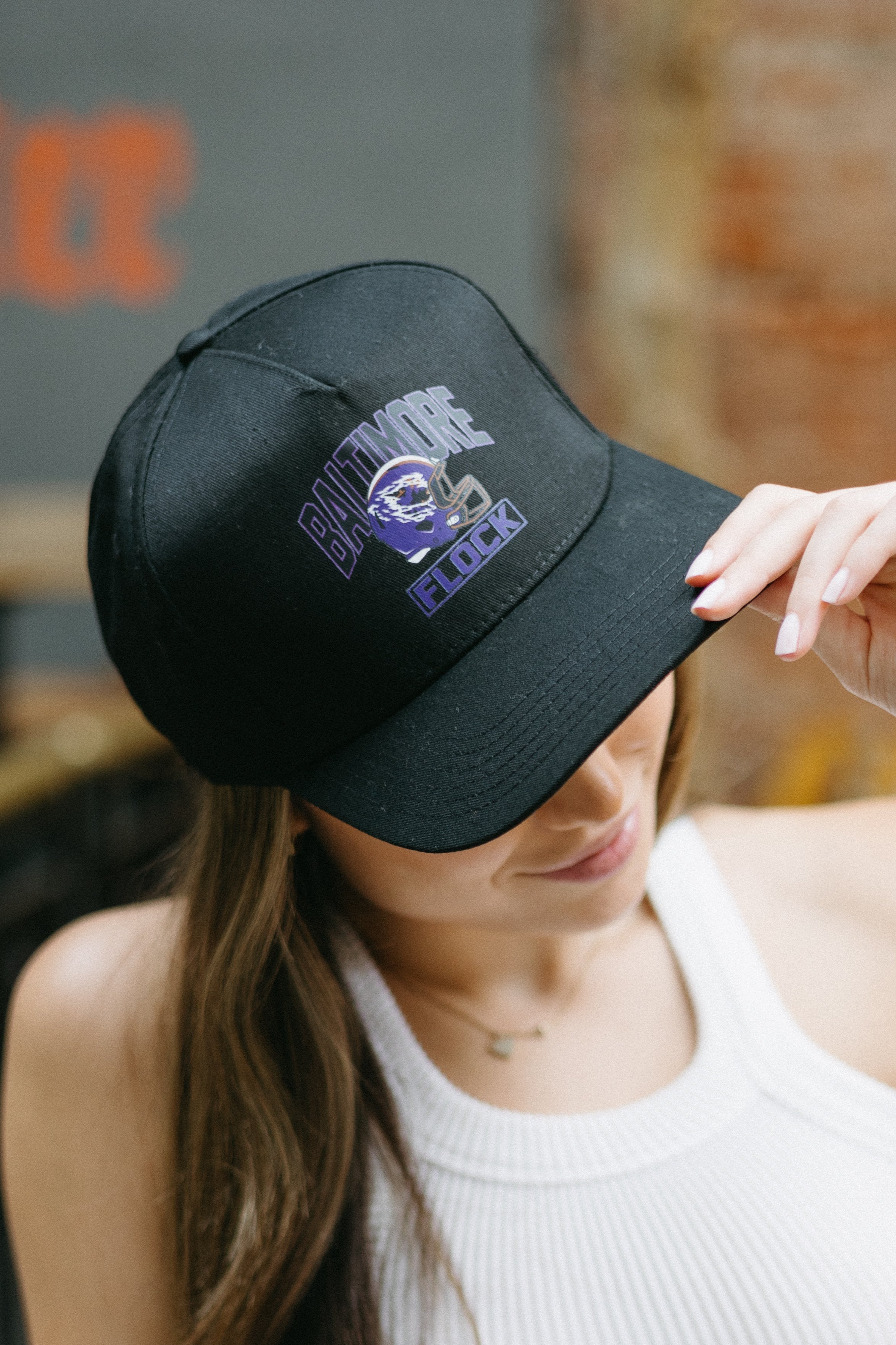 A person wearing a black snapback hat with 'Baltimore' text and a football graphic in purple on the front.