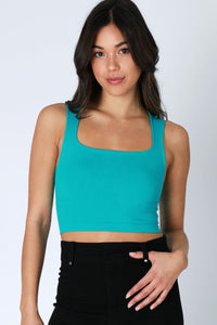 Woman wearing a teal crop top and black pants on a white background