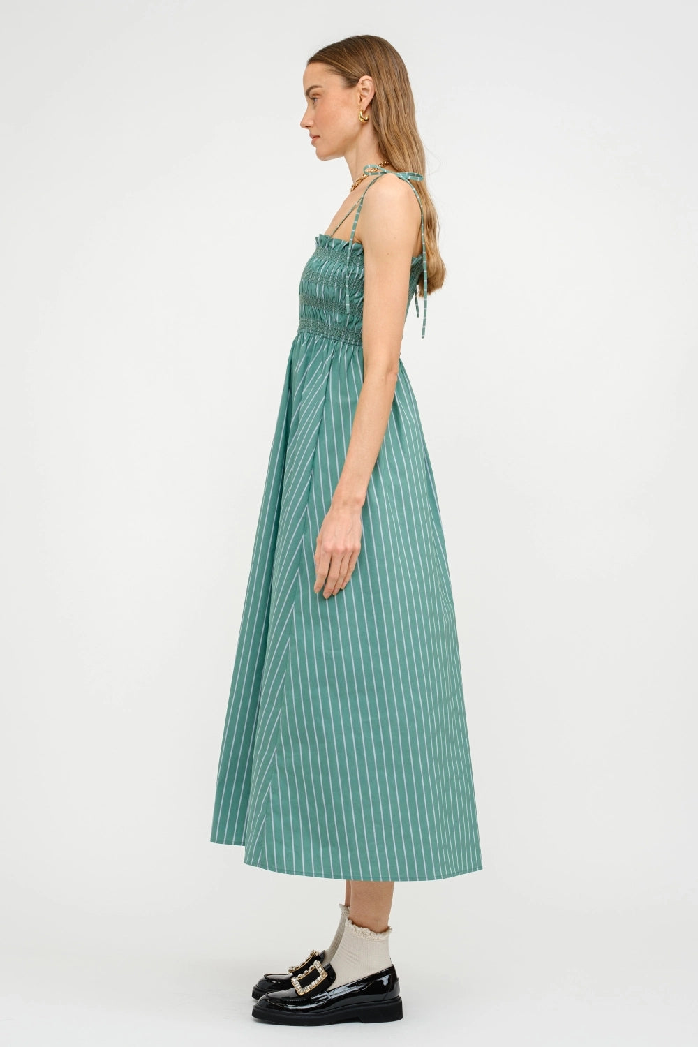 Woman wearing a green pleated dress on a white background