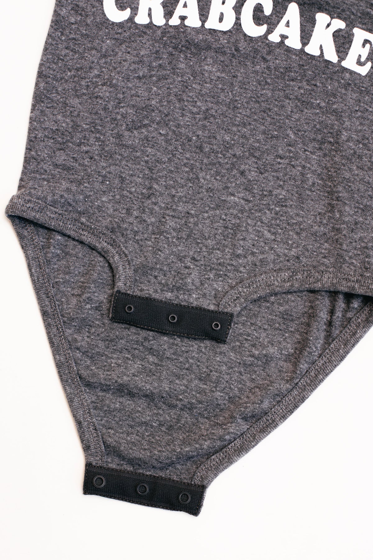 Gray baby romper with 'CRABCAKE' text on a white background