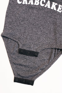 Gray baby romper with 'CRABCAKE' text on a white background