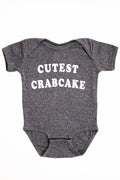Gray baby onesie with 'CUTEST CRABCAKE' text on a white background
