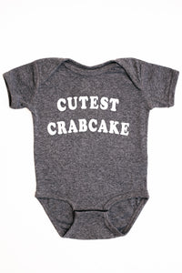 Gray baby onesie with 'CUTEST CRABCAKE' text on a white background