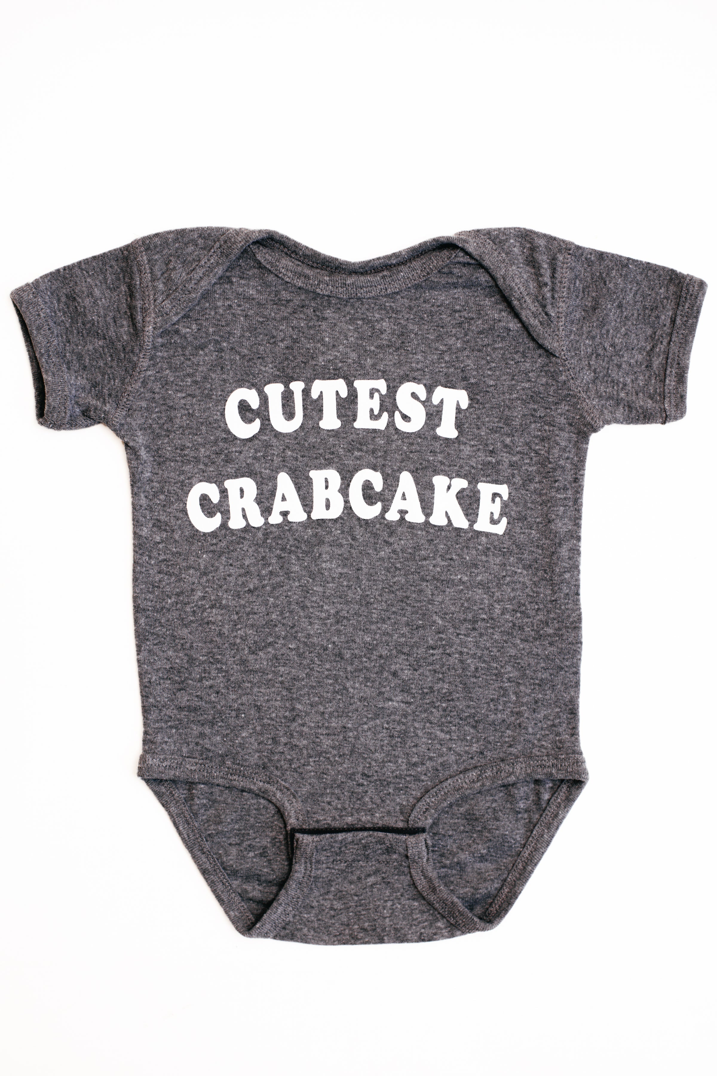 Gray baby onesie with 'CUTEST CRABCAKE' text on a white background
