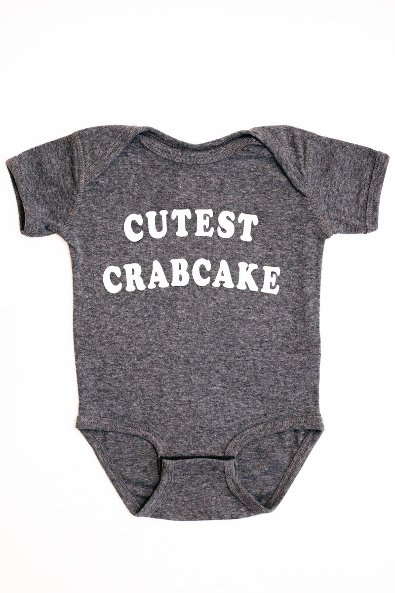 Gray baby onesie with 'CUTEST CRABCAKE' text on a white background
