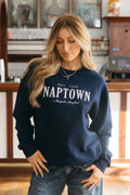 A person wearing a navy crewneck sweatshirt with 'NAPTOWN' written in white text on the front.