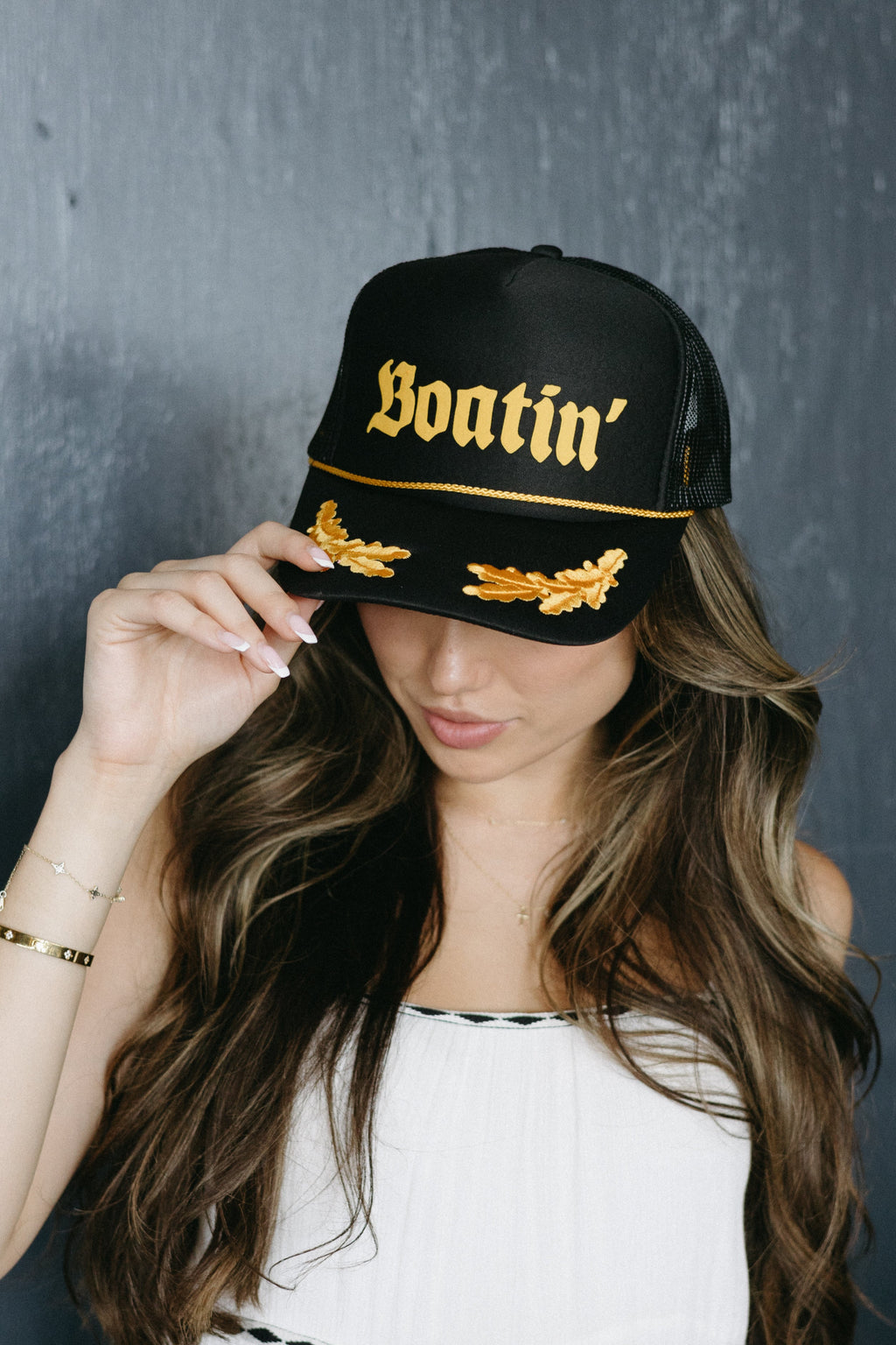 Woman wearing a black cap with gold text against a dark background
