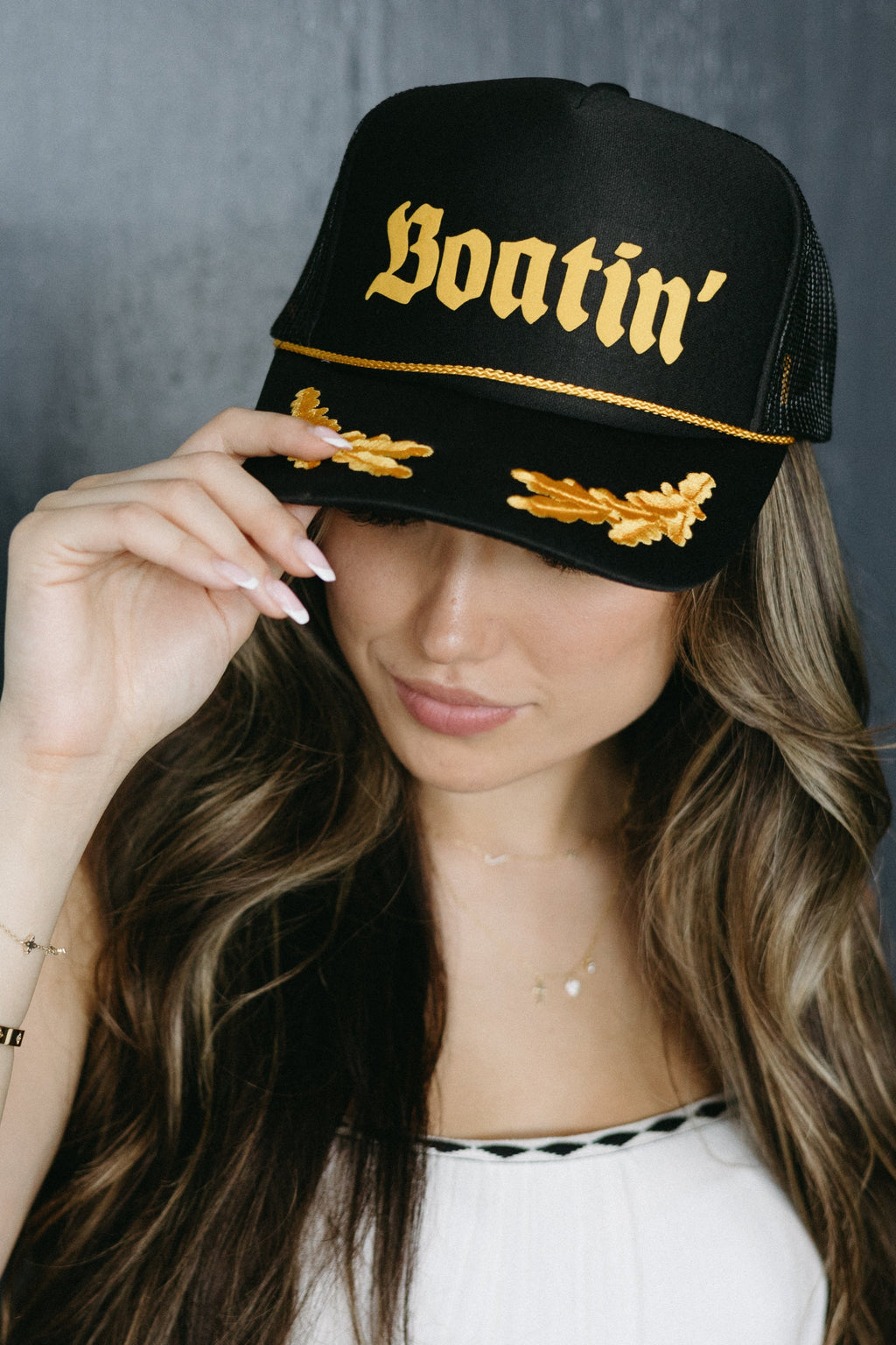 Woman wearing a black cap with gold text against a dark background