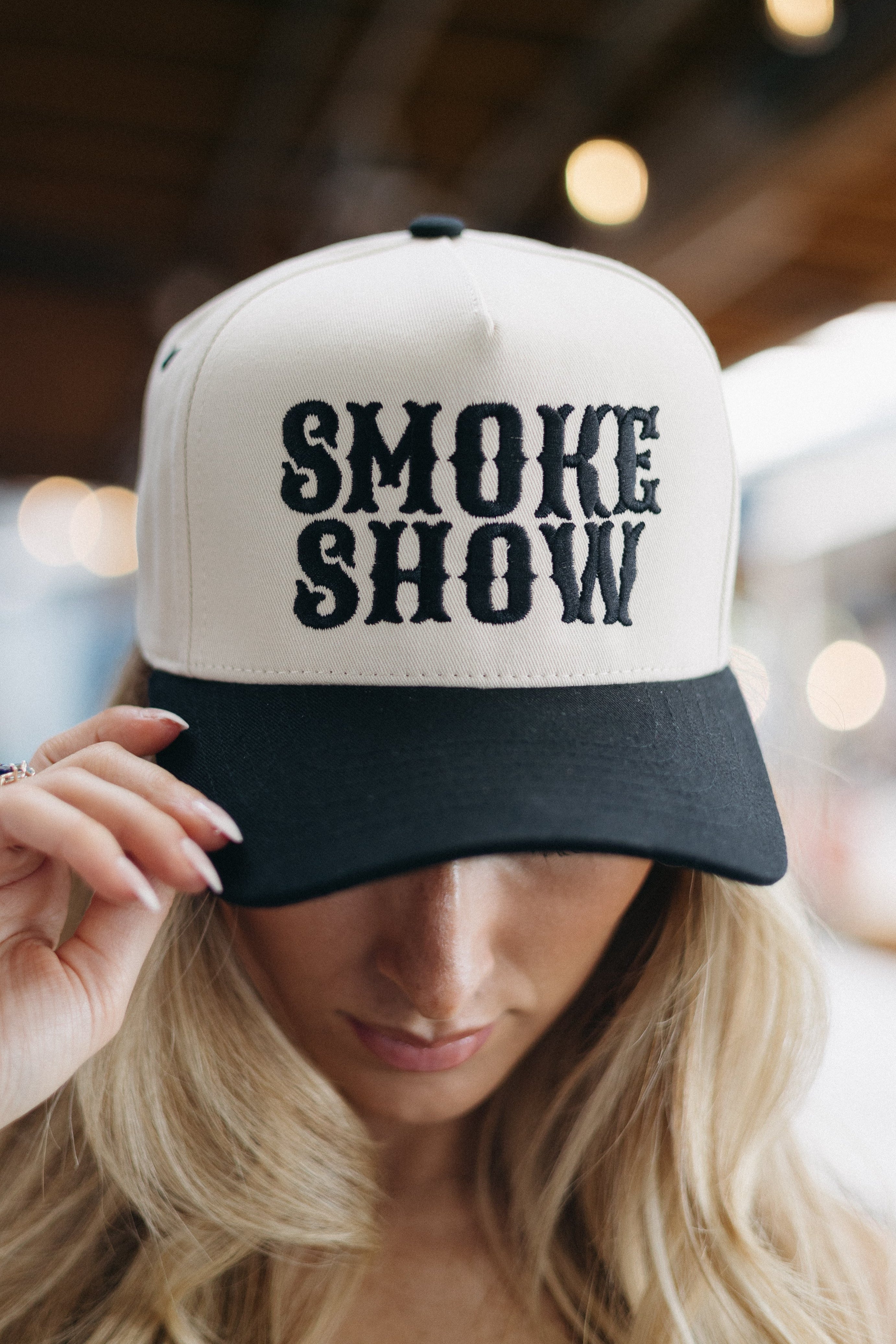 Person wearing a cap with 'SMOKE SHOW' text in an indoor setting