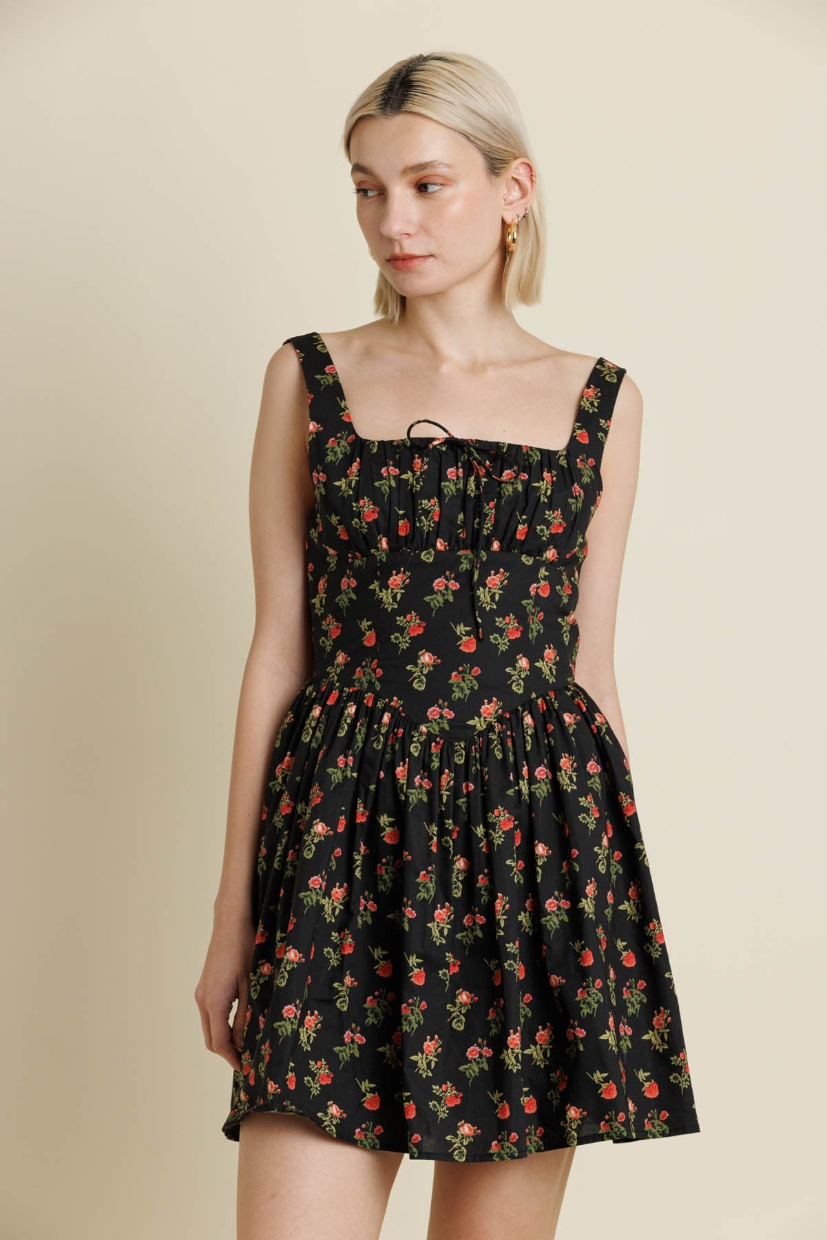 Woman wearing a black floral dress against a beige background