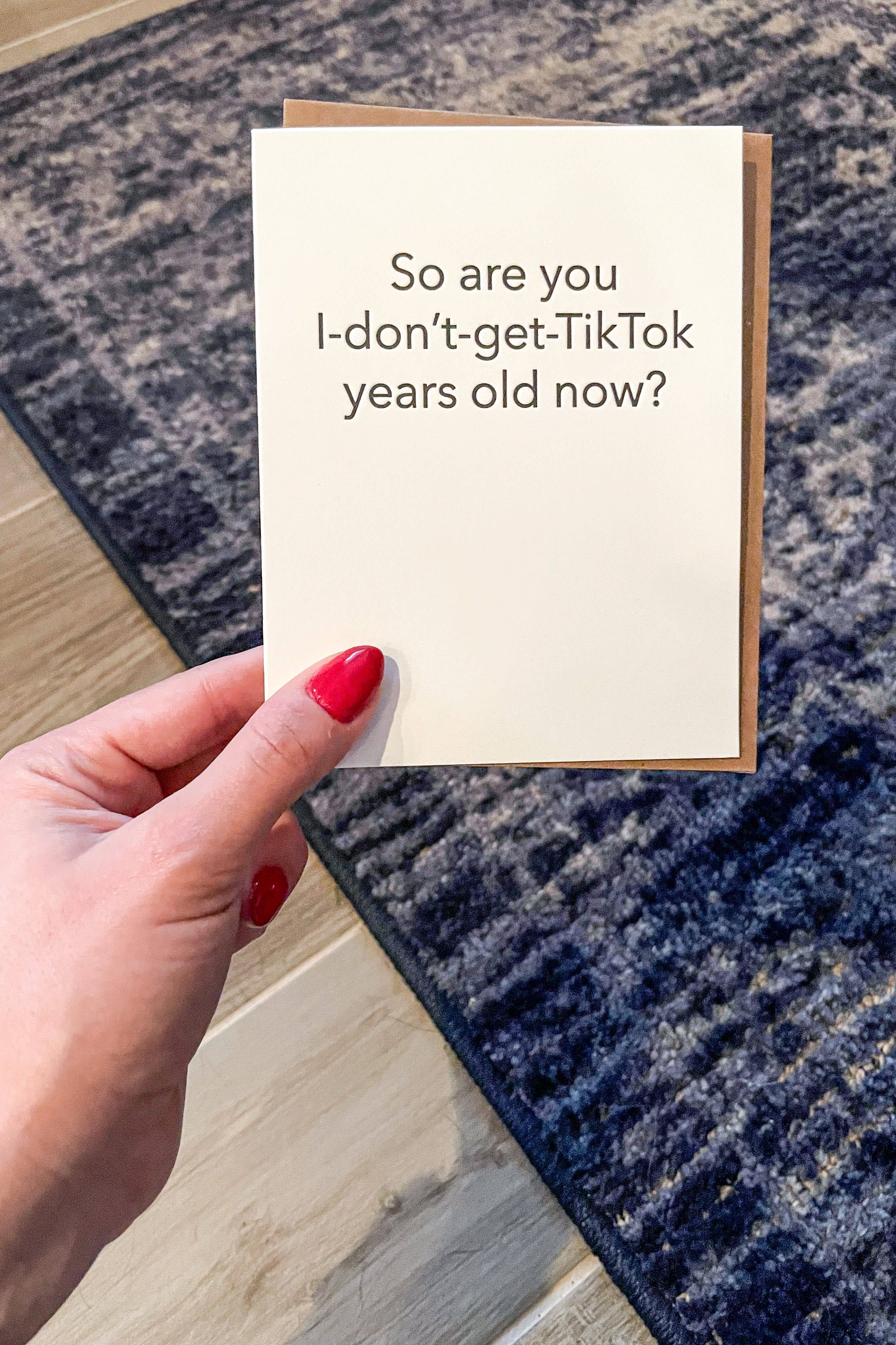 Hand holding a card with text on a blue and gray patterned rug