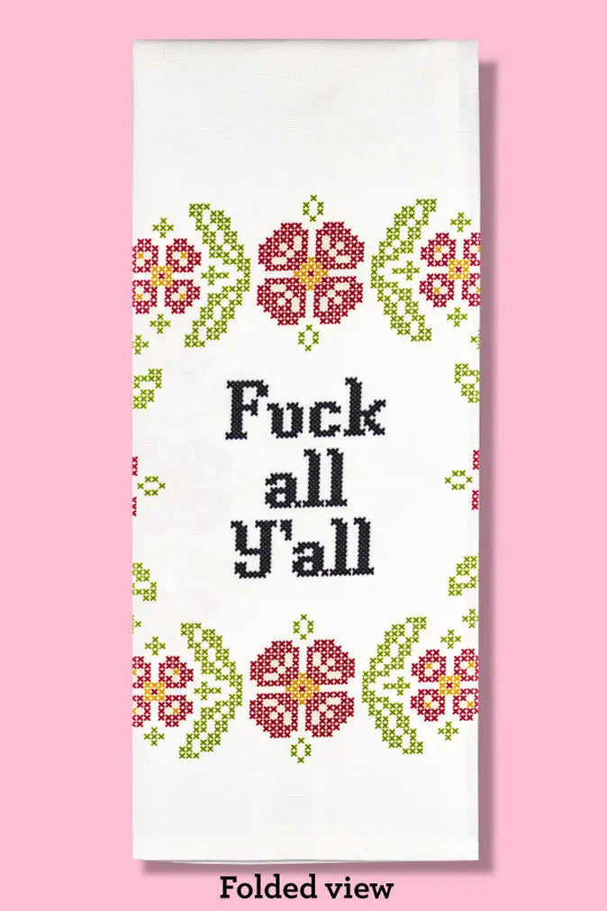 This image displays a bold and expressive dishtowel titled "Fuck All Y'all". The towel measures 17 inches by 28 inches and features a striking printed design that reads "Fuck all Y'all" in a bold, black font, centered within a vibrant pattern of colorful flowers and leaves in shades of pink, green, and yellow.